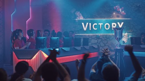 Two Esport Teams of Pro Gamers Play in RPG Strategy Video Game on a Championship Arena, Happy Red Team Wins Round and Celebrates with High-Fives.Big Screen Showing Mock-up Gameplay. Cyber Games