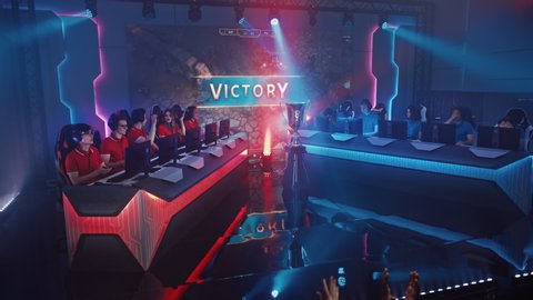 Two Esport Teams of Pro Gamers Play in RPG Strategy Video Game on a Championship Arena, Happy Team Wins Round and Celebrates with High-Fives.Big Screen Showing Mock-up Gameplay. Cyber Games Tournament