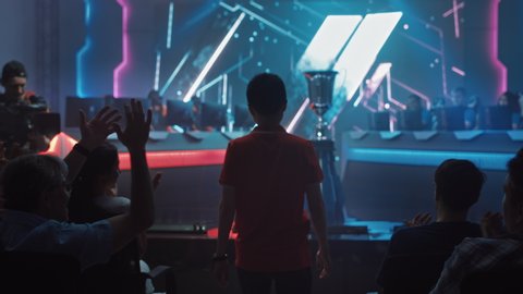 Esport Professional Gamer Enters Video Game Championship Arena. Cyber Games Tournament Event with Crowd of Fans and Spectators Cheering for Favourite Players. Online Streaming Entertainment
