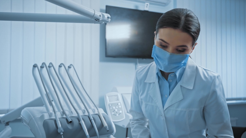 Dentist in latex gloves switching lamp and examining patient teeth in clinic | Shutterstock HD Video #1056637763