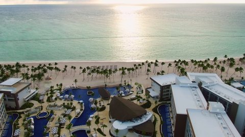 Tropical beach and resort in sunrise, luxury resort with sand beach, palm trees and pool area in the Dominican Republic, beautiful getaway oasis, aerial view