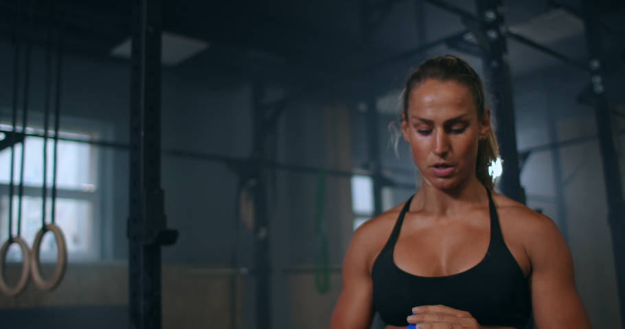 A tired female athlete in the gym drinks water from a bottle after training | Shutterstock HD Video #1056640889