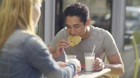 Cute Couple On A Date, Young Man Takes A Big Bite Of A Cookie, Then Dunks It In Milk (4K)
