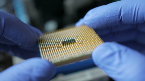 CPU in hands of a technician. The processor is being examined for apparent defects. In Modern Electronic Manufacturing Factory Design Engineer Holds Microchip  . Close-up a New Generation Microchip.