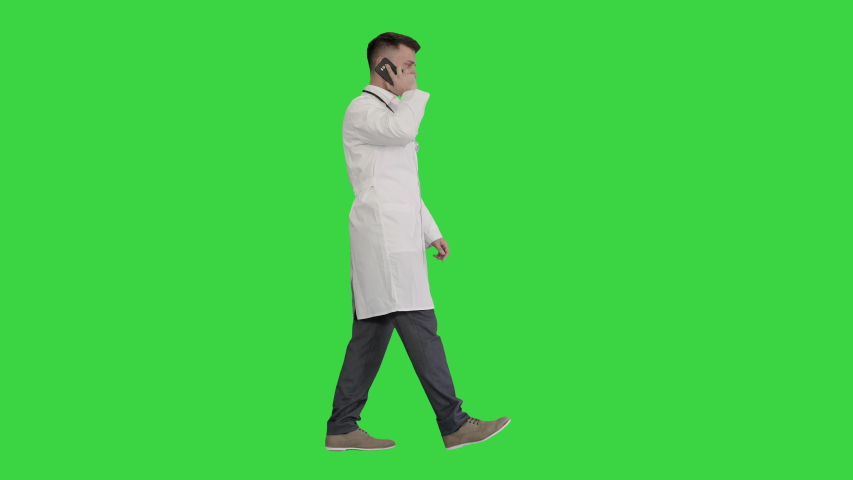 Medical doctor calling by phone walking on a Green Screen, Chroma Key. | Shutterstock HD Video #1056646445