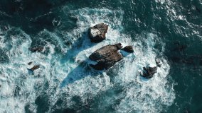 Giant waves crashing at rocky sea cliffs with splashing white foam. Breathtaking top aerial slow motion view of azure ocean. Cinematic 4K drone nature video. Outdoor adventure and ocean background. 