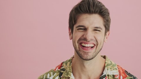 A laughing young man is smiling on isolated over a pink background in studio.