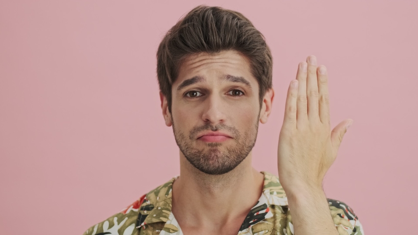 A handsome young man is changing his facial emotions isolated over a pink background.