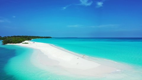 Paradise tropical island with long stripe of white sandy beach surrounded by blue azure sea water under a bright blue sky in Maldives