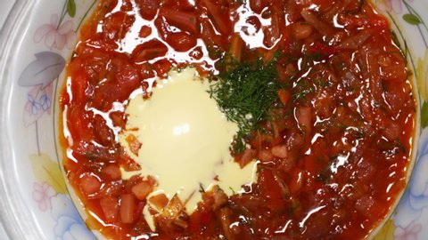 Bowl of homemade red borscht with smetana rotating in microwave top view. Portion of traditional Ukrainian Russian sour soup microwaving.