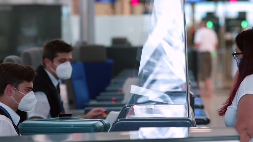 Checking counter documents registration flights at airport. An airline representative wearing mask on face makes passenger registration. Travel during quarantine of the coronavirus infection COVID-19. Royalty-Free Stock Footage #1056652043