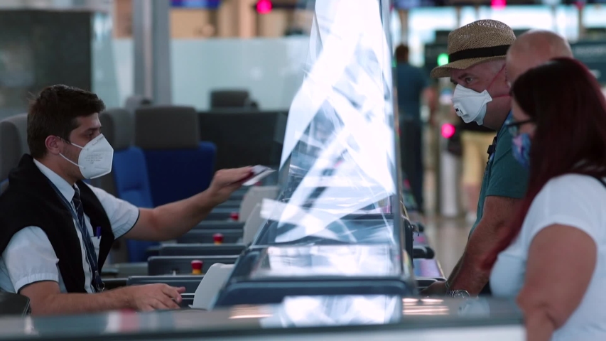 Checking counter documents registration flights at airport. An airline representative wearing mask on face makes passenger registration. Travel during quarantine of the coronavirus infection COVID-19.