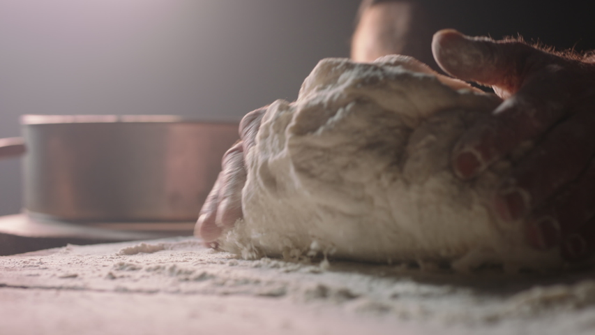 Closeup shot of hands of senior bakery chef applying flour on dough, old man kneading dough, making bread using traditional recipe, isolated on black background 4k footage Royalty-Free Stock Footage #1056653168