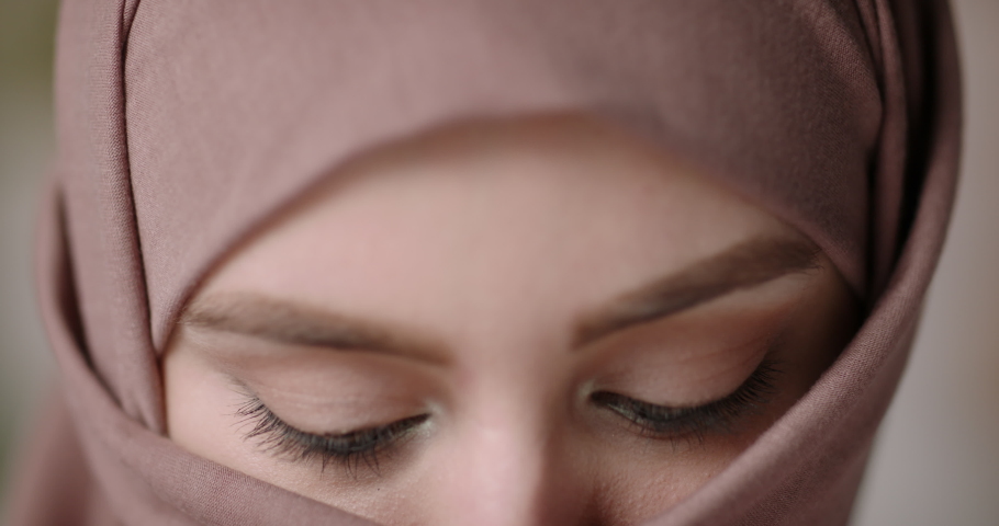 Face with natural make up of attractive muslim gir wearing traditional hijab scarf. Her brown and green eyes looking at camera - beauty, islam concept extreme close up 4k footage | Shutterstock HD Video #1056653285
