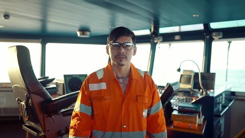 Filipino deck Officer on bridge of vessel or ship wearing coverall during navigaton watch at sea