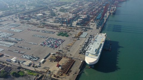 Aerial view of the huge ro-ro ship loading new cars. Automotive container carriers oversea services. Transportation business for prefabricated cars by sea freight
