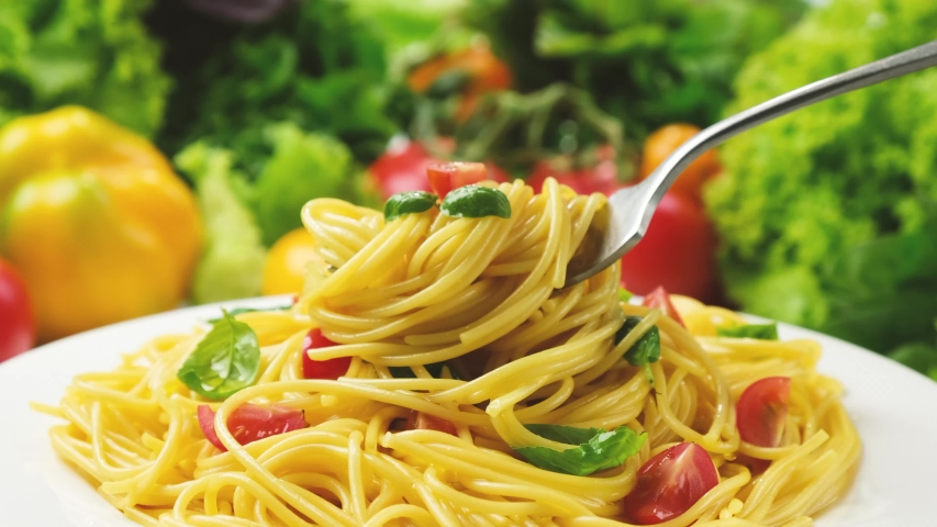 Plate of cooked italian pasta, spaghetti on fork with tomatoes and basil leaves, 4K UHD video footage