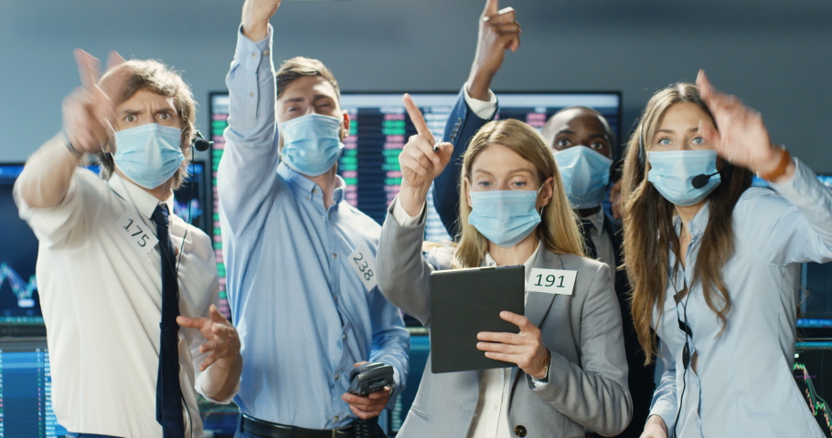 Mixed-races traders in medical masks selling and buying at stock market on trading floor at exchange. Change office. Multiethnic men and women screaming when putting rates. Woman with tablet device. Royalty-Free Stock Footage #1056665345