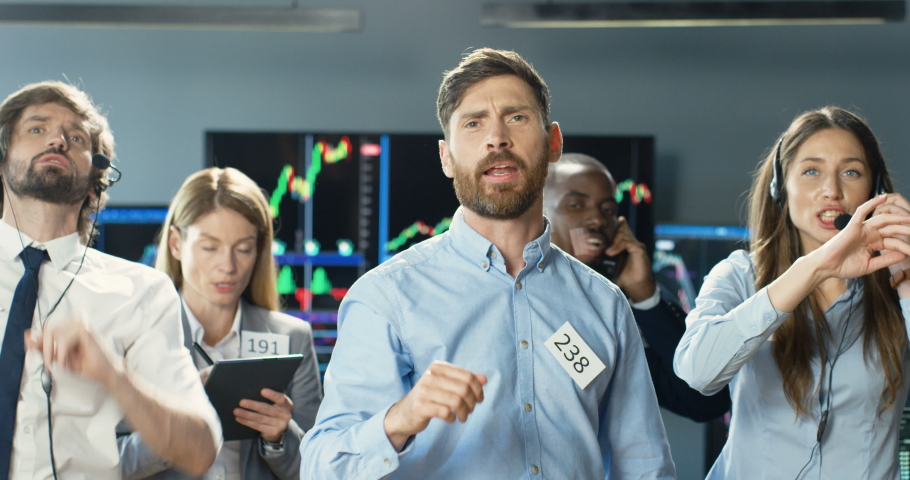 Caucasian young man broker selling or buying on stock market with group of mixed-races colleagues. Male trader putting bets and rates at exchange. Mixed-races co-workers of trading screaming. Royalty-Free Stock Footage #1056665348