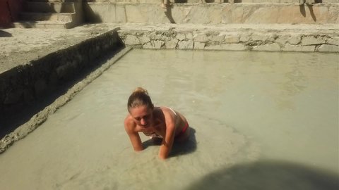 Young woman taking mud bath outdoors in Dalyan, Turkey