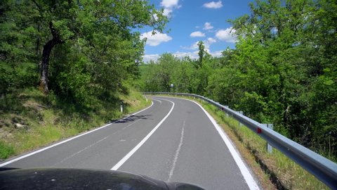 A turn on a beautiful asphalt road. Solid line on a two-way track.
POV of driving travel on highway road among forest in countryside. Blue sky with white clouds White posts at the edges of the highway