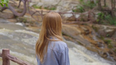 A young woman visits waterfall in mountains. Travel to Dalat concept
