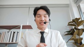 Young Asian male confident support service representative talking to web camera. Asian Businessman in headset communicates by conference video call.