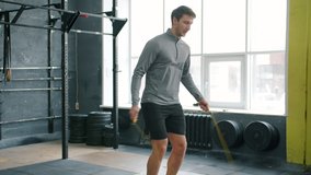 Handsome young sportsman is skipping with jumping rope indoors in gym focused on cardio exercise training alone. People, lifestyle and sports concept. - Powered by Shutterstock - Get 15% off with code: PIKWIZARD15