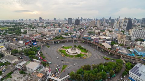 Time lapse of aerial view of Victory Monument on busy street road. Roundabout in Bangkok Downtown Skyline. Thailand. Financial district center in smart urban city. Skyscrapers at sunset.
