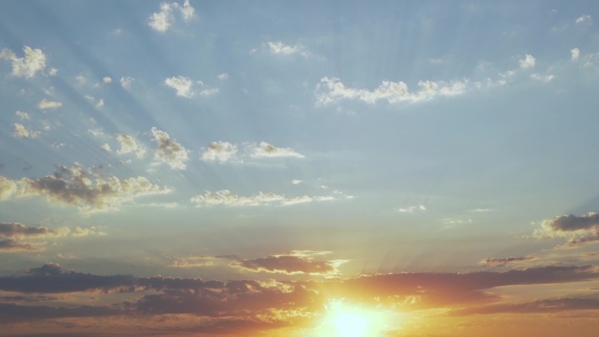 Colorful Quick Time Laps of the Sunset over the Horizon is 4K. Time lapse of Clouds at Sunset Illuminated by the Sun 4K. Rays and Glare of the Sun through the Clouds. Royalty-Free Stock Footage #1056677183