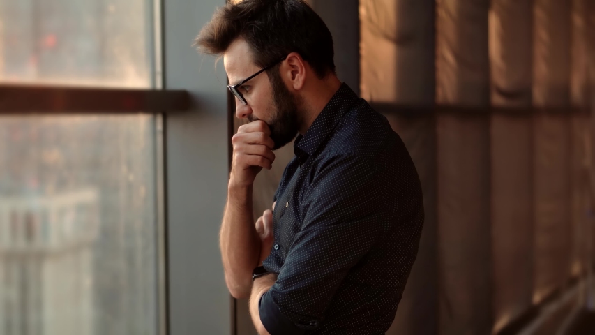 Disappointed Businessman Looking Out Of Window.Creative Man Standing Near Windows In Office.Thoughtful Serious Businessman Thinking Of Business Deal Idea And Looking Away.Executive Boss CEO Dreaming | Shutterstock HD Video #1056677810