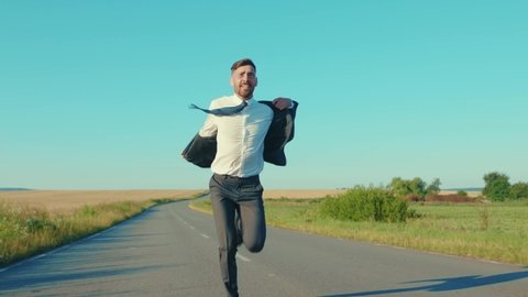 Successful businessman runs removes the jacket country road near a wheat field freedom concept outdoors handsome winner jumping elegant slow motion