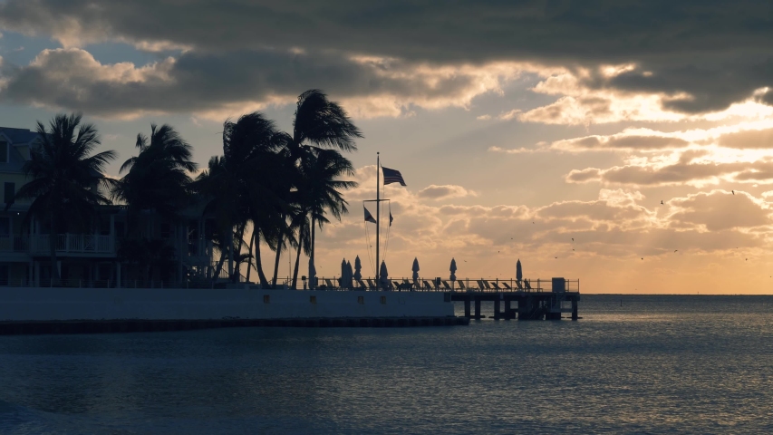 Beautiful sunrise on Key West, Florida, USA. With palms and resorts on background. Sunset over the sea at Key West, Florida. America flag waving in the wind, key west, Florida