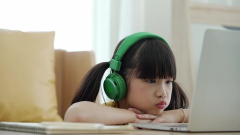 Little Asian girl in headphone studying online interact with computer notebook, Internet e-learning concept