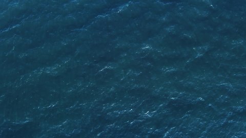 Texture of water surface of sea reflection of sun's rays. Sun glare on blue water aerial view from drone at low altitude on sunset summer. Motion of small waves. Sea idyll. Relax