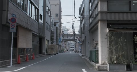 Walking across typical street in Tokyo at sunset. Small empty street with garbage containers