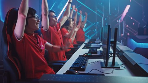 Two Esport Teams of Pro Gamers Play in Mock-up FPS Shooter Video Game on a Championship, Happy Team Wins Celebrates with High-Fives. Cyber Games Arena Broadcasting Tournament. Arc Shot Slow Motion