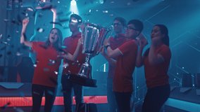 Diverse Esport Team Winner of the Video Games Tournament Celebrates Victory Cheering and Lifting Trophy in Big Championship Arena. Cyber Gaming Event with Gamers and Fans. Elevating Slow Motion Shot