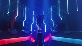 eSports Winner Trophy Standing on a Stage in the Middle of the Computer Video Games Championship Arena. Two Rows of PC for Competing Teams. Stylish Neon Lights with Cool Area Design. Zoom out Dolly