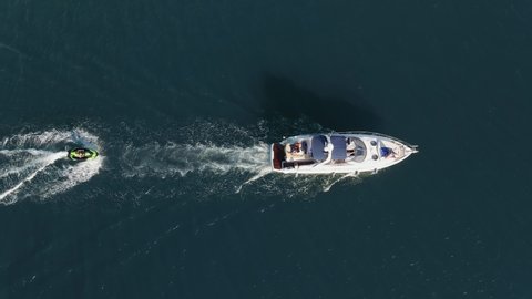 White luxury motor yacht sailing with water scooter on blue sea surface with small waves in sea aerial view drone. Tourists strolling boat. White path on water from boat. Recreation. Relax. Top view