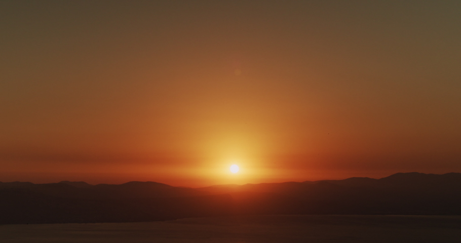 Beautiful landscape with sunset over the big lake and the mountains. Tilting up to down shot.