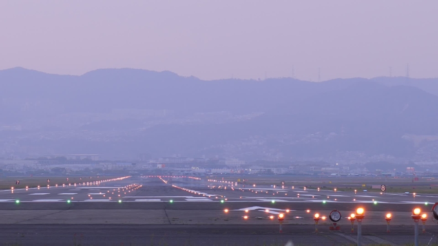 Slow motion shot of landing jet liner, rear view from end of runway. Passenger plane fly down and touch ground. Evening time shot of Itami Airport air traffic Royalty-Free Stock Footage #1056691799
