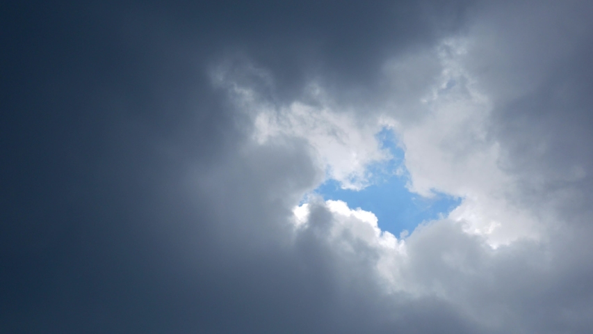 Dense rain clouds slowly closing the hole with a piece of blue sky
