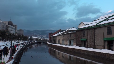 OTARU, HOKKAIDO, JAPAN - FEBRUARY 2020 : Scenery of OTARU CANAL in winter snow season. Popular tourist destination for Japanese and foreign visitors. Time lapse shot sunset to night.