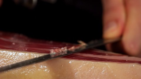 Ham cutter with his knife on a extra detailed image cutting a thin slice of Iberico jamon, short-waisted image. very appetizing the public eager to feed on this delicacy shoot