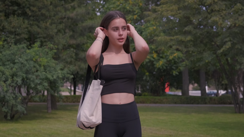 Beautiful girl with an eco bag. A smiling nice girl fix her hair and walk in the park.