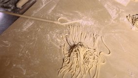 Cook prepares Italian pasta noodles on wooden table in restaurant kitchen.Traditional noodle recipe from Italy.Chef cooks food from white wheat flour in pasteria,filmed from above