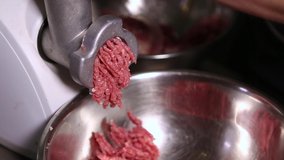 Kitchen meat grinder chops beef meat into patty for hamburgers in close up video clip.Natural red steak mincing with mincer machine in closeup footage filmed in Italian restaurant kitchen