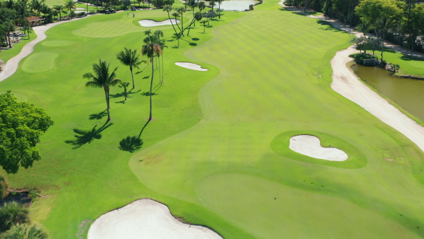 Aerial footage of people on a golf course playing the sport match in Miami, Florida, USA. Cinematic overhead view on active men playing the golf game on a sunny summer day. Background for business Royalty-Free Stock Footage #1056699035