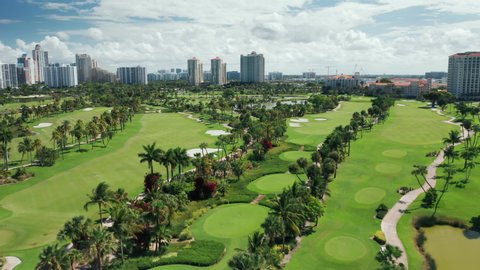Cinematic overhead view on beautiful golf course on a sunny summer day. 4K aerial footage of cinematic Miami skyline on a background, Florida, USA. Great footage for the golf sport business commercial